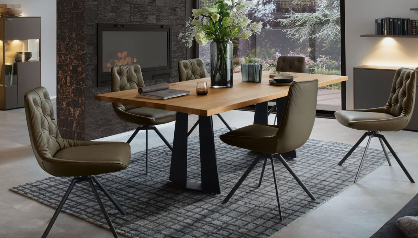 Modernes Esszimmer mit dem Venjakob Tisch Chic Holztisch, sechs Stühlen, einem Teppich, einem gemütlichen Kamin und einem großen Fenster mit Blick in den Garten. Modernes Esszimmer mit dem Venjakob Tisch Chic Holztisch, sechs Stühlen, einem Teppich, einem gemütlichen Kamin und einem großen Fenster mit Blick in den Garten.