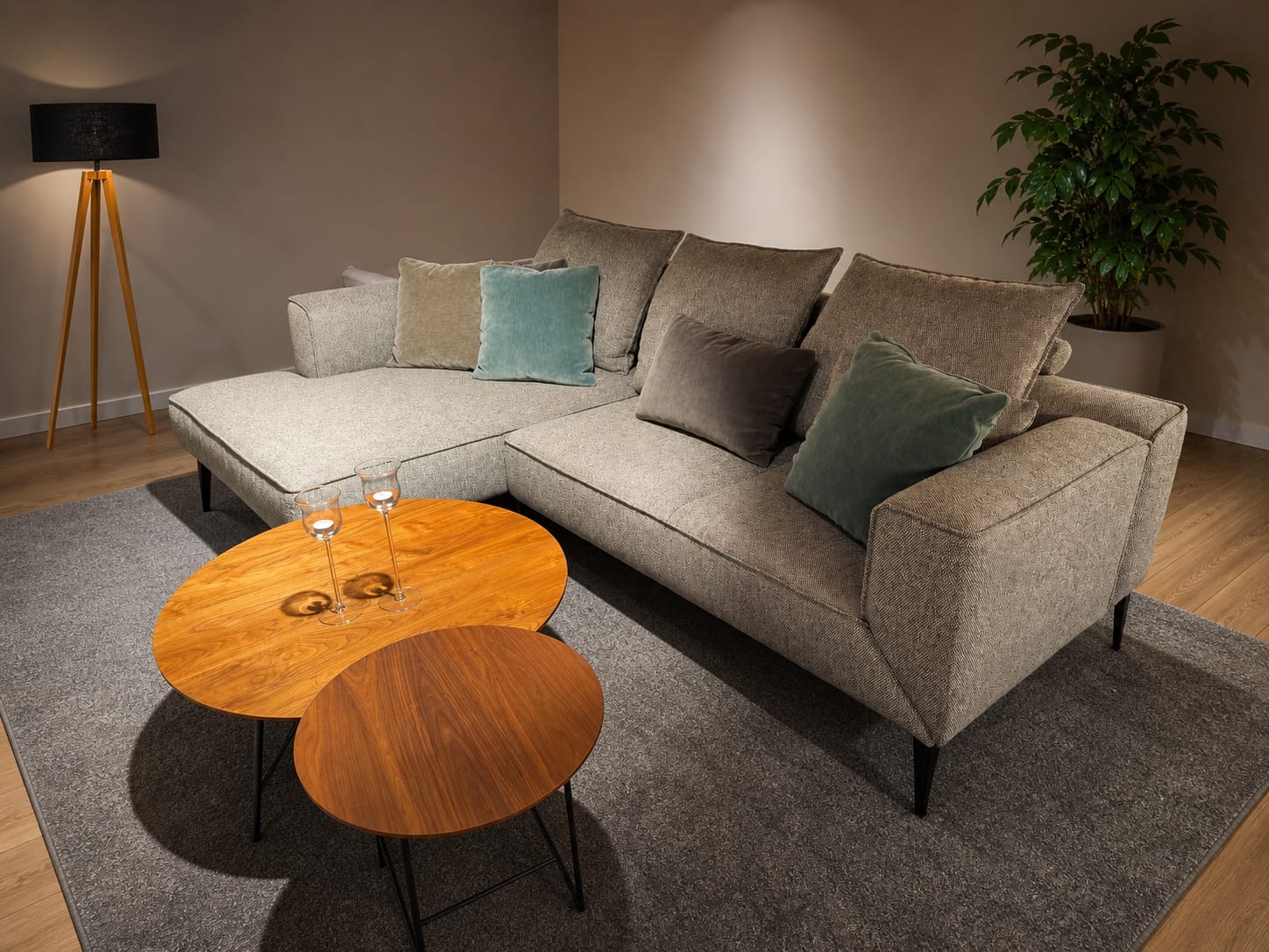 Modernes Wohnzimmer mit dem grauen Sektionssofa Jori Loungeville Landscape, runden Holztischen, einer Stehlampe und einer Topfpflanze. Modernes Wohnzimmer mit dem grauen Sektionssofa Jori Loungeville Landscape, runden Holztischen, einer Stehlampe und einer Topfpflanze.