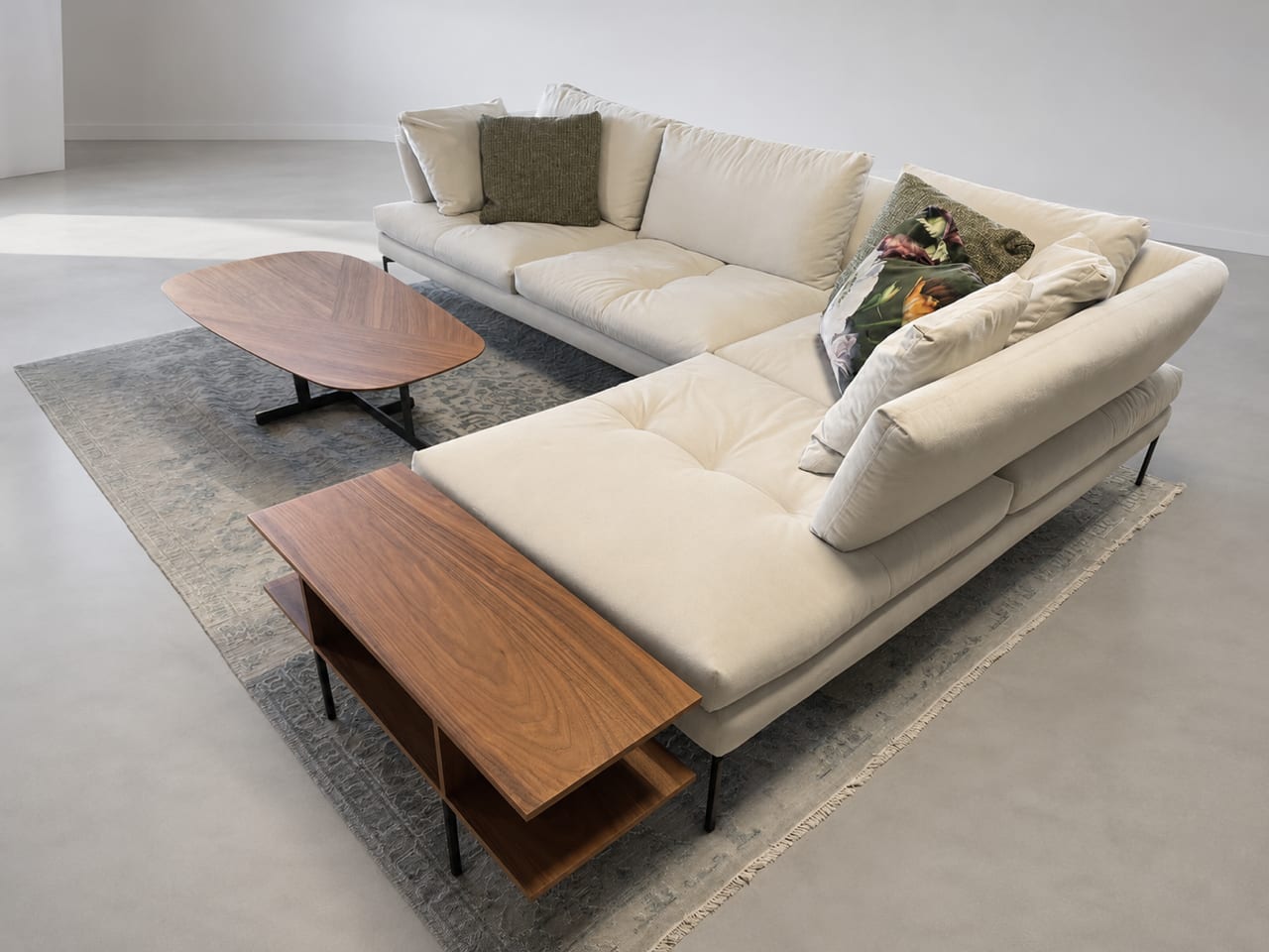 Das Bonaldo Sofa Aliante in Beige, gepaart mit dekorativen Kissen, zwei Couchtischen aus Holz und einem Teppich auf einem hellen Boden. Das Bonaldo Sofa Aliante in Beige, gepaart mit dekorativen Kissen, zwei Couchtischen aus Holz und einem Teppich auf einem hellen Boden.