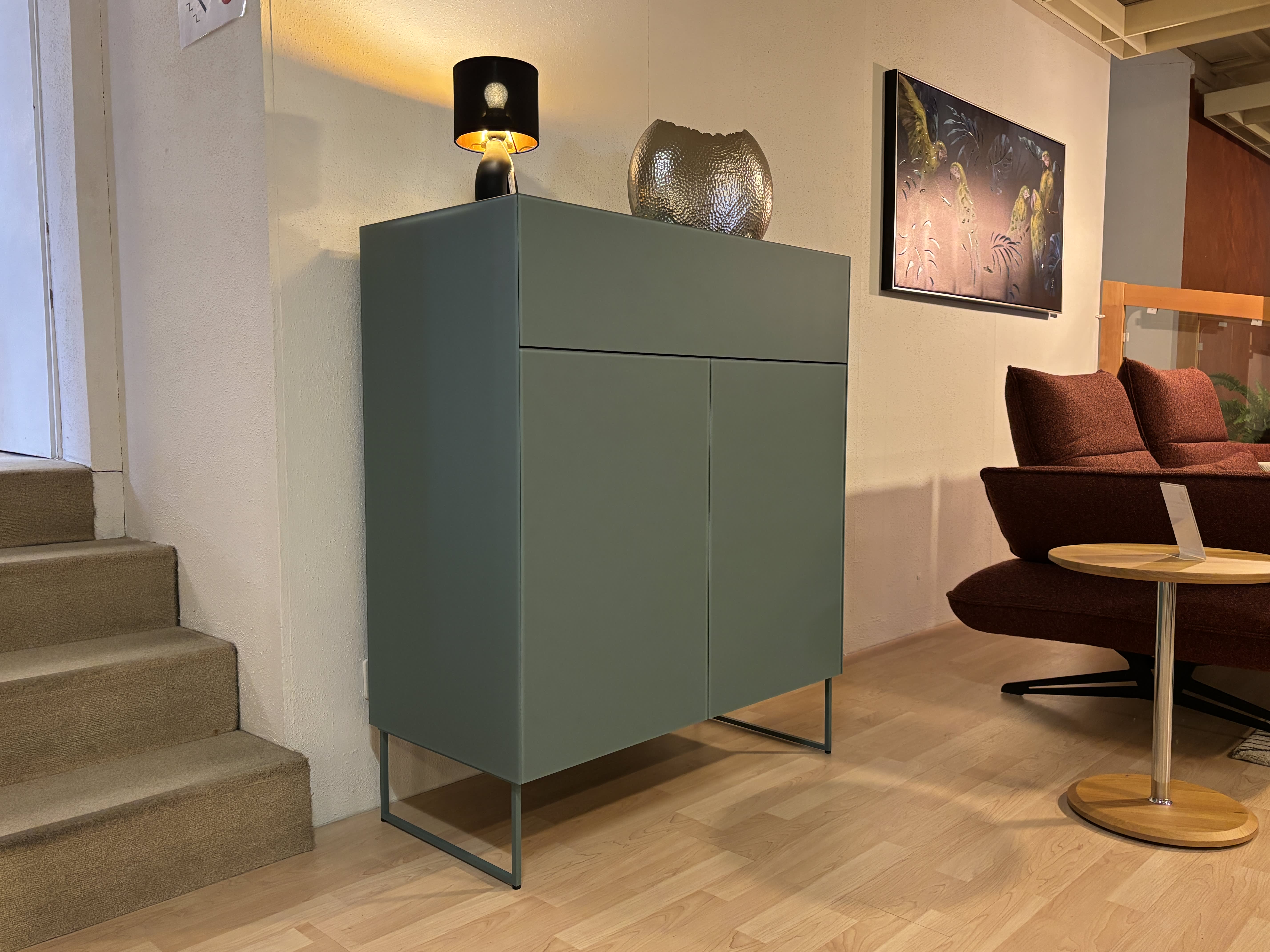 Das Spectral Sideboard 101cm, in modernem Grün, steht neben der Treppe und einem roten Stuhl auf einem Holzboden, gekrönt von einer Lampe und Dekor. Das Spectral Sideboard 101cm, in modernem Grün, steht neben der Treppe und einem roten Stuhl auf einem Holzboden, gekrönt von einer Lampe und Dekor.