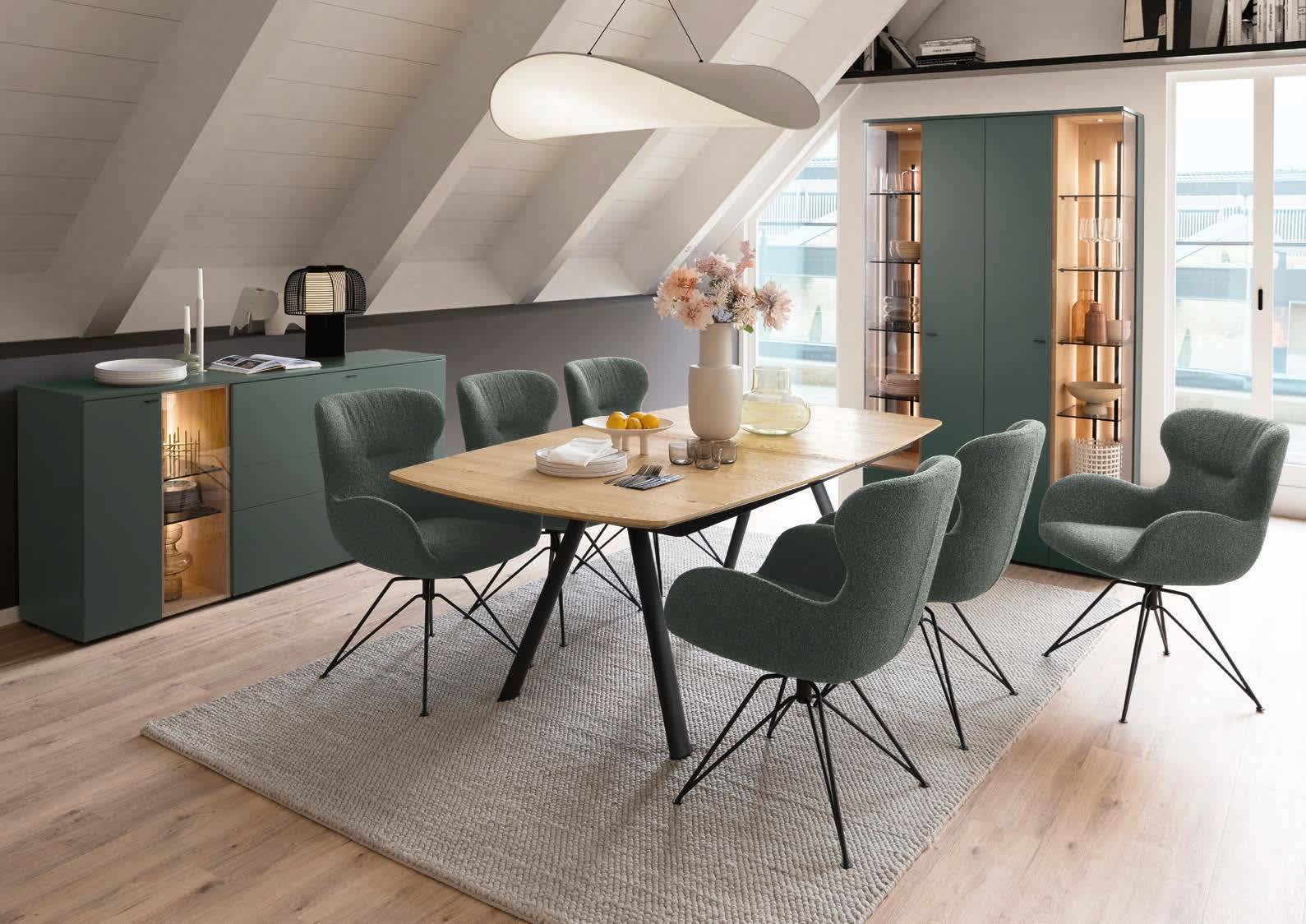 Modernes Esszimmer eingerichtet mit dem Venjakob Wohnprogramm Vanya: Holztisch, sechs grüne Stühle, Sideboard, Schränke und stilvolles Dekor. Modernes Esszimmer eingerichtet mit dem Venjakob Wohnprogramm Vanya: Holztisch, sechs grüne Stühle, Sideboard, Schränke und stilvolles Dekor.