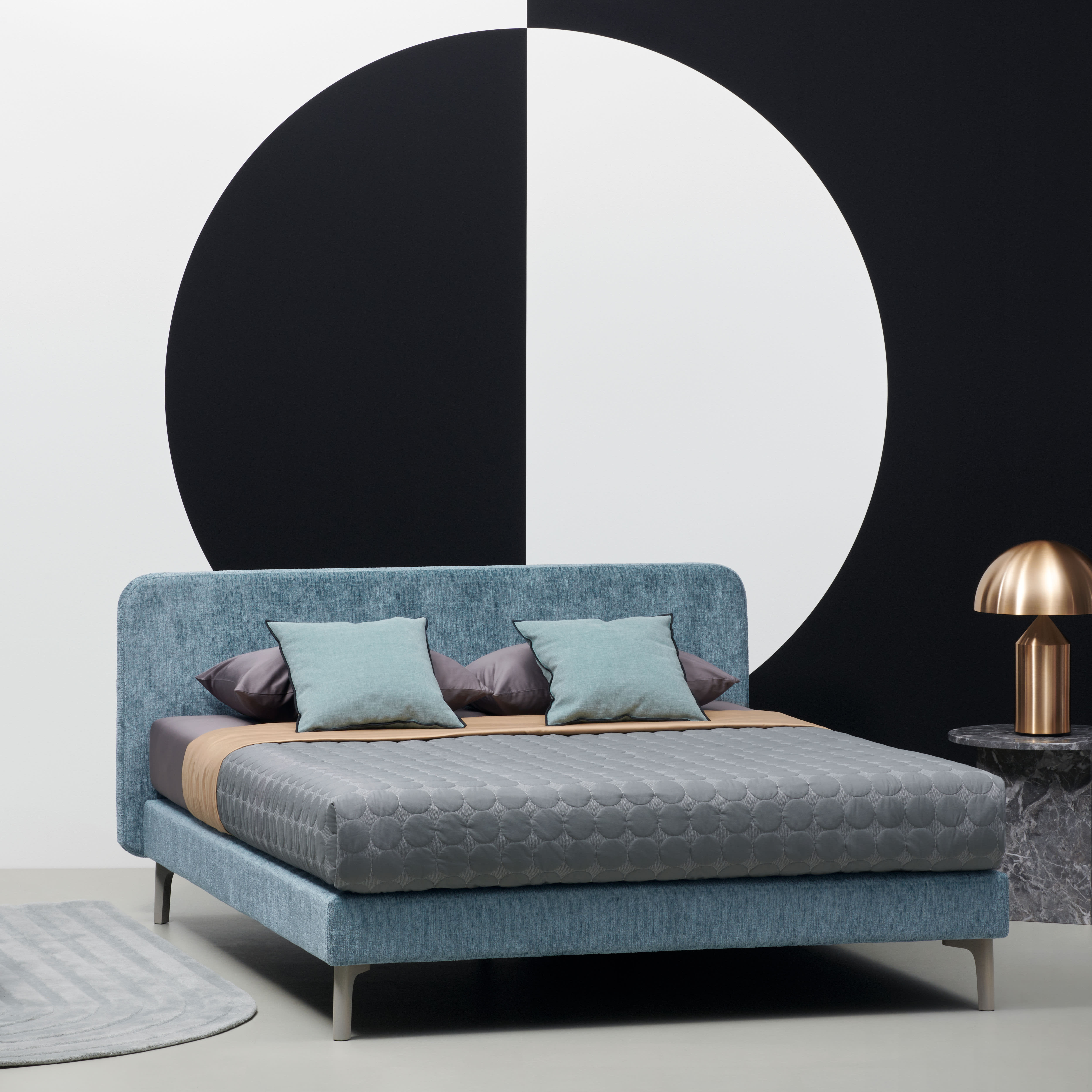 Une chambre moderne avec le lit boxspring Riposa Slow en bleu, avec une literie grise et une œuvre murale géométrique frappante en noir et blanc. Une chambre moderne avec le lit boxspring Riposa Slow en bleu, avec une literie grise et une œuvre murale géométrique frappante en noir et blanc.