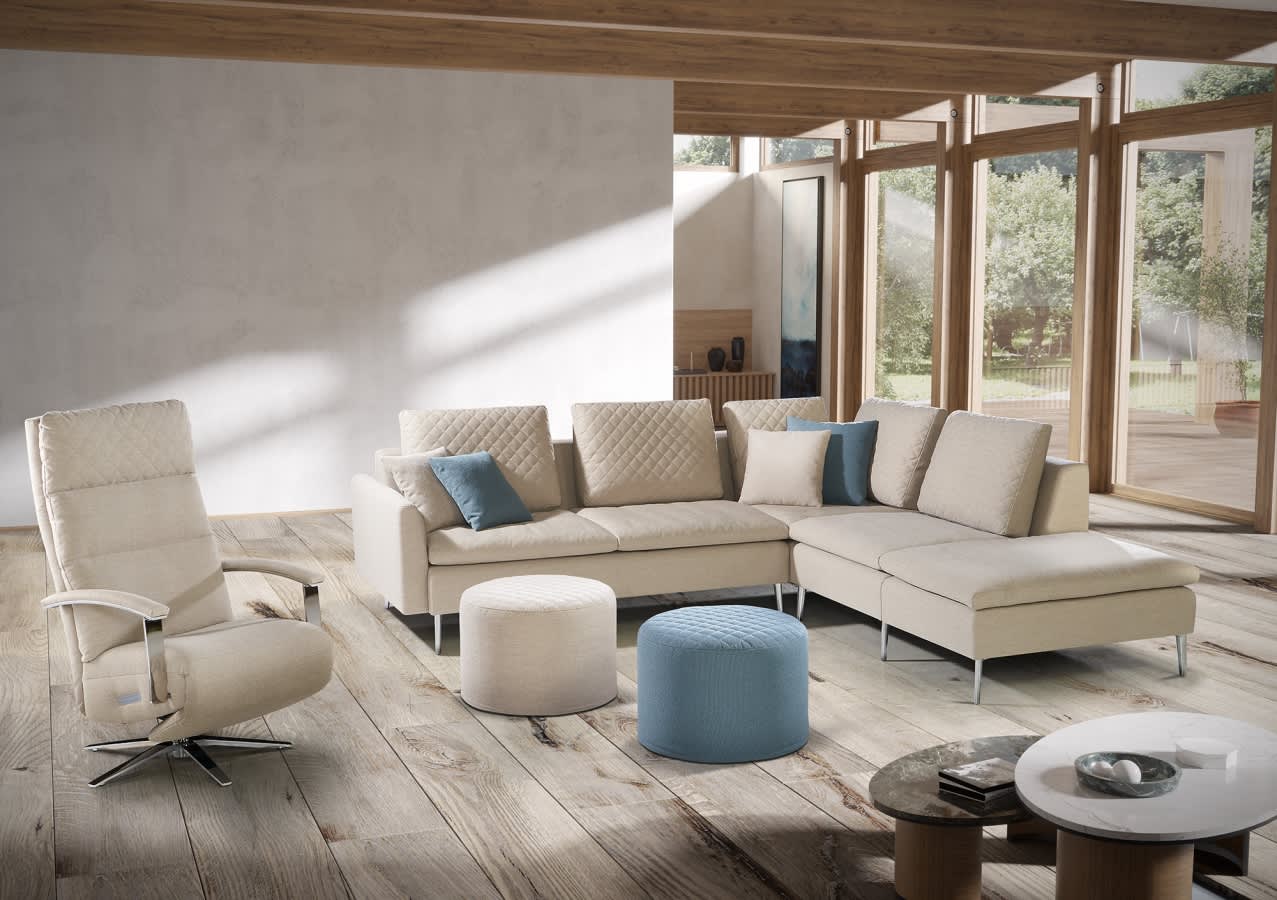 Modernes Wohnzimmer mit dem Artanova Sofa Dyo 9192, einem Sessel, runden Hockern und großen Fenstern mit Blick ins Grüne. Modernes Wohnzimmer mit dem Artanova Sofa Dyo 9192, einem Sessel, runden Hockern und großen Fenstern mit Blick ins Grüne.