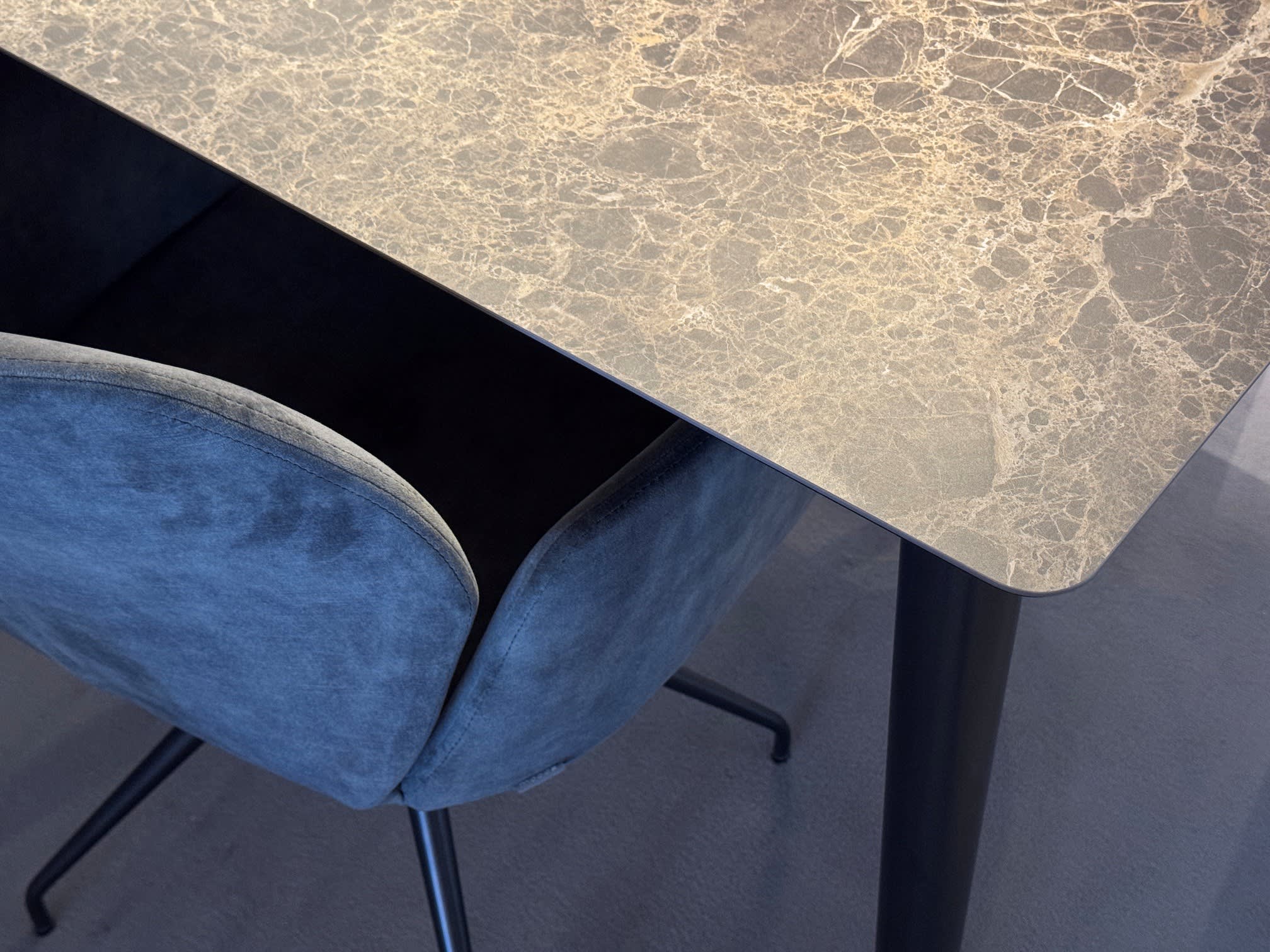 Der Mobitec Tisch Terra T0300 mit Marmorplatte steht zusammen mit einem dunklen Sessel aus Samt auf einem grauen Boden, schräg von oben gesehen. Der Mobitec Tisch Terra T0300 mit Marmorplatte steht zusammen mit einem dunklen Sessel aus Samt auf einem grauen Boden, schräg von oben gesehen.