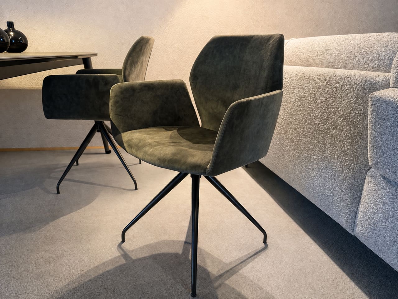 Der Mobitec Stuhl Mood 95, ein moderner grüner Drehstuhl mit Metallbeinen, steht neben einem grauen Sofa und einem dunklen Tisch in einem modernen Raum. Der Mobitec Stuhl Mood 95, ein moderner grüner Drehstuhl mit Metallbeinen, steht neben einem grauen Sofa und einem dunklen Tisch in einem modernen Raum.