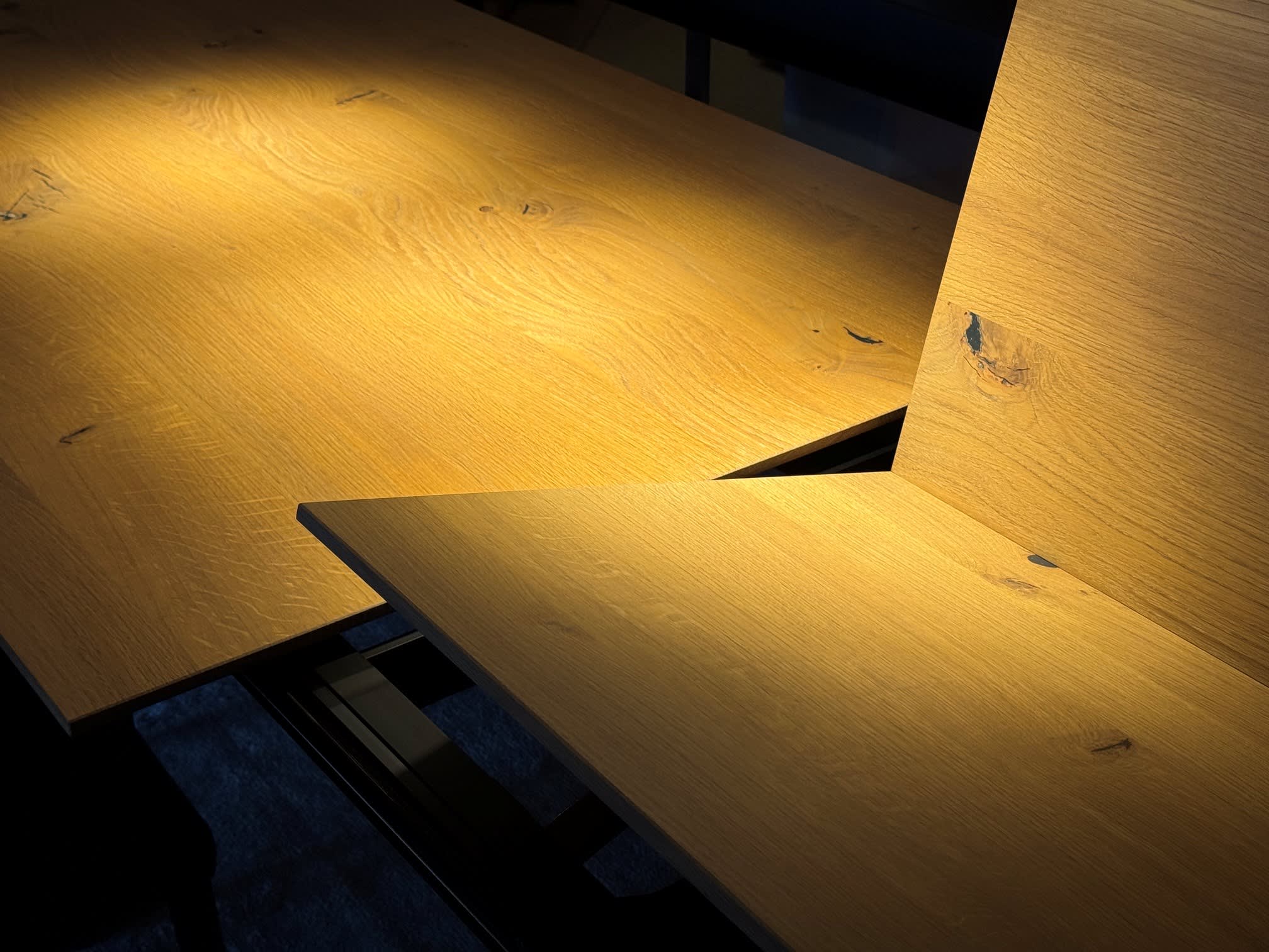 Das Sonnenlicht beleuchtet die natürliche Maserung und die dunklen Äste der schrägen Holzbretter des Girsberger Auszugstisches Bela und setzt warme Akzente. Das Sonnenlicht beleuchtet die natürliche Maserung und die dunklen Äste der schrägen Holzbretter des Girsberger Auszugstisches Bela und setzt warme Akzente.