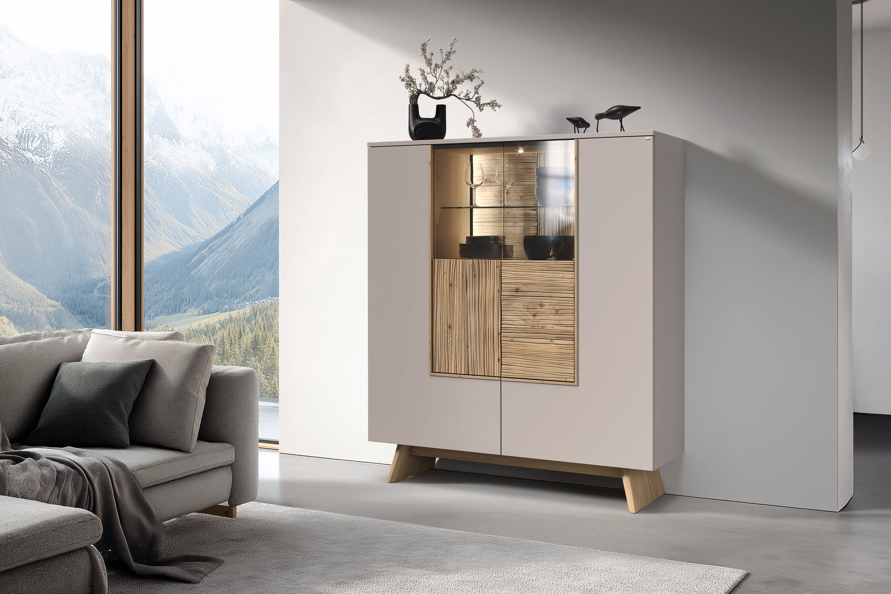 Das Voglauer Sideboard Lacera mit seinen Holz- und Glastüren wird in einem hellen Wohnzimmer mit Vasen und Skulpturen geschmückt. Das Voglauer Sideboard Lacera mit seinen Holz- und Glastüren wird in einem hellen Wohnzimmer mit Vasen und Skulpturen geschmückt.