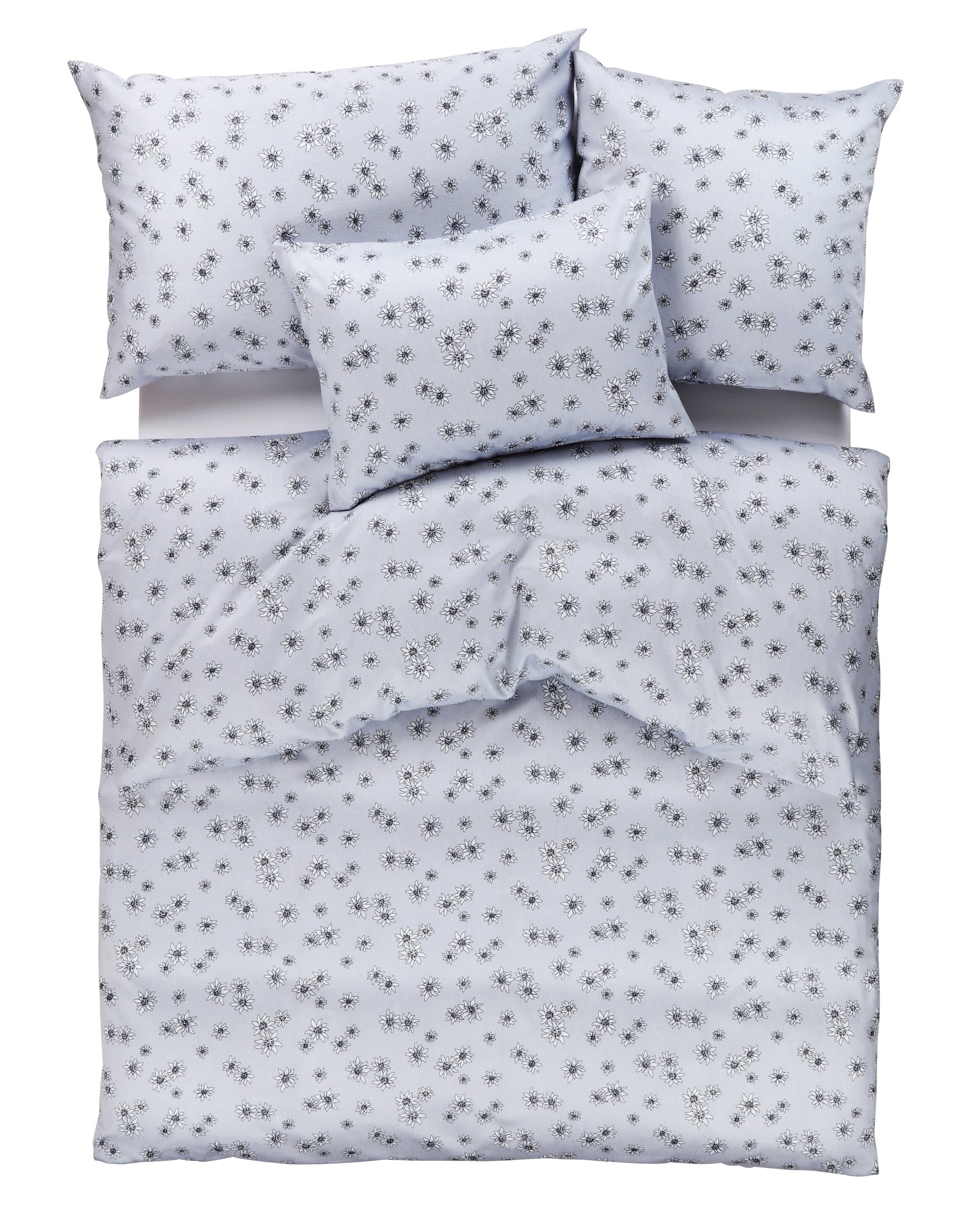 Ein ordentlich gemachtes Bett mit weißer Bettwäsche und Kissenbezügen mit einem kleinen schwarzen Blumenmuster. Ein ordentlich gemachtes Bett mit weißer Bettwäsche und Kissenbezügen mit einem kleinen schwarzen Blumenmuster.