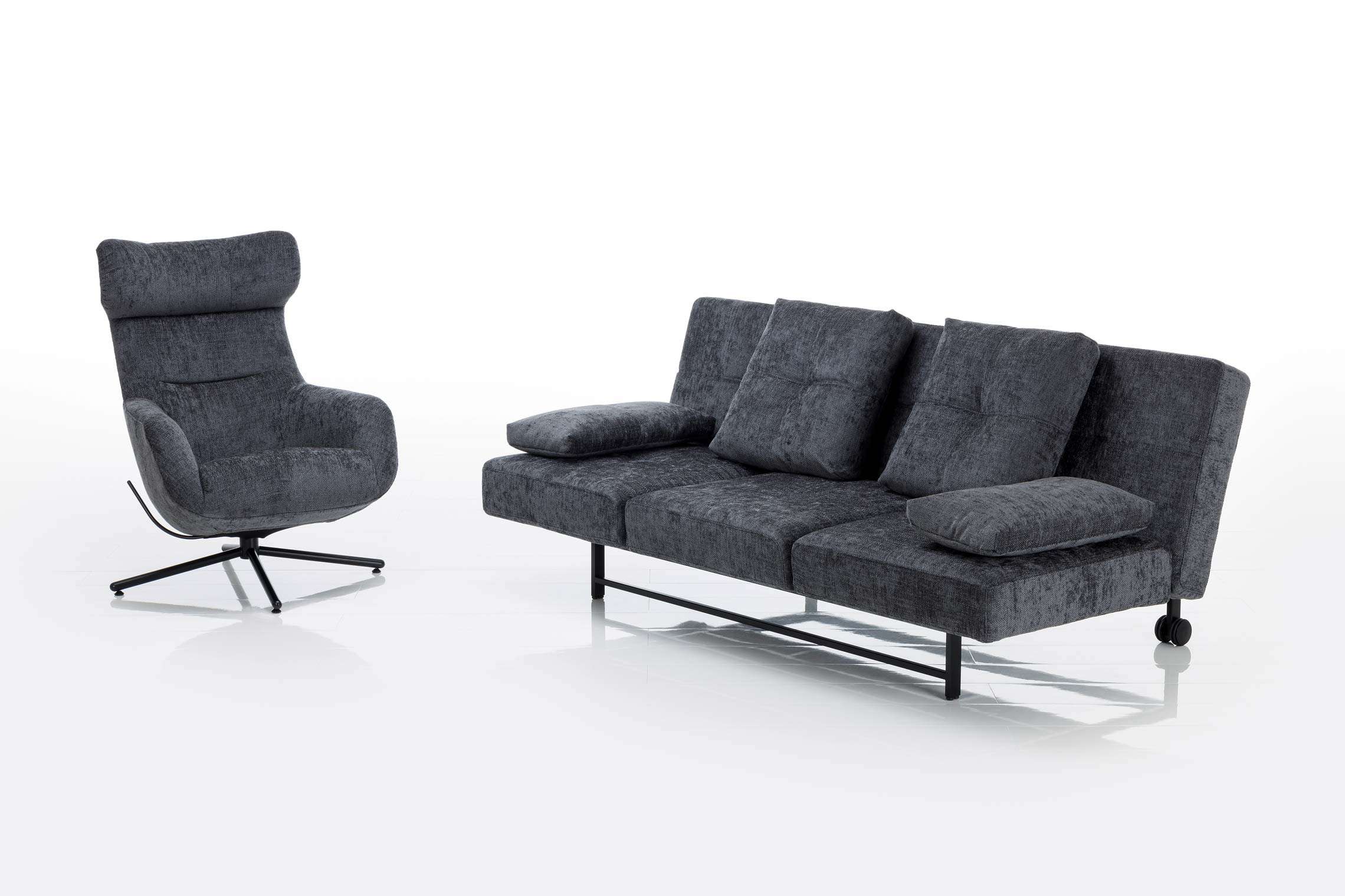Brühl Funktionssofa Cross Over: Dunkelgrauer Sessel und passendes Dreisitzer-Sofa mit Kissen, abgebildet vor weißem Hintergrund. Brühl Funktionssofa Cross Over: Dunkelgrauer Sessel und passendes Dreisitzer-Sofa mit Kissen, abgebildet vor weißem Hintergrund.