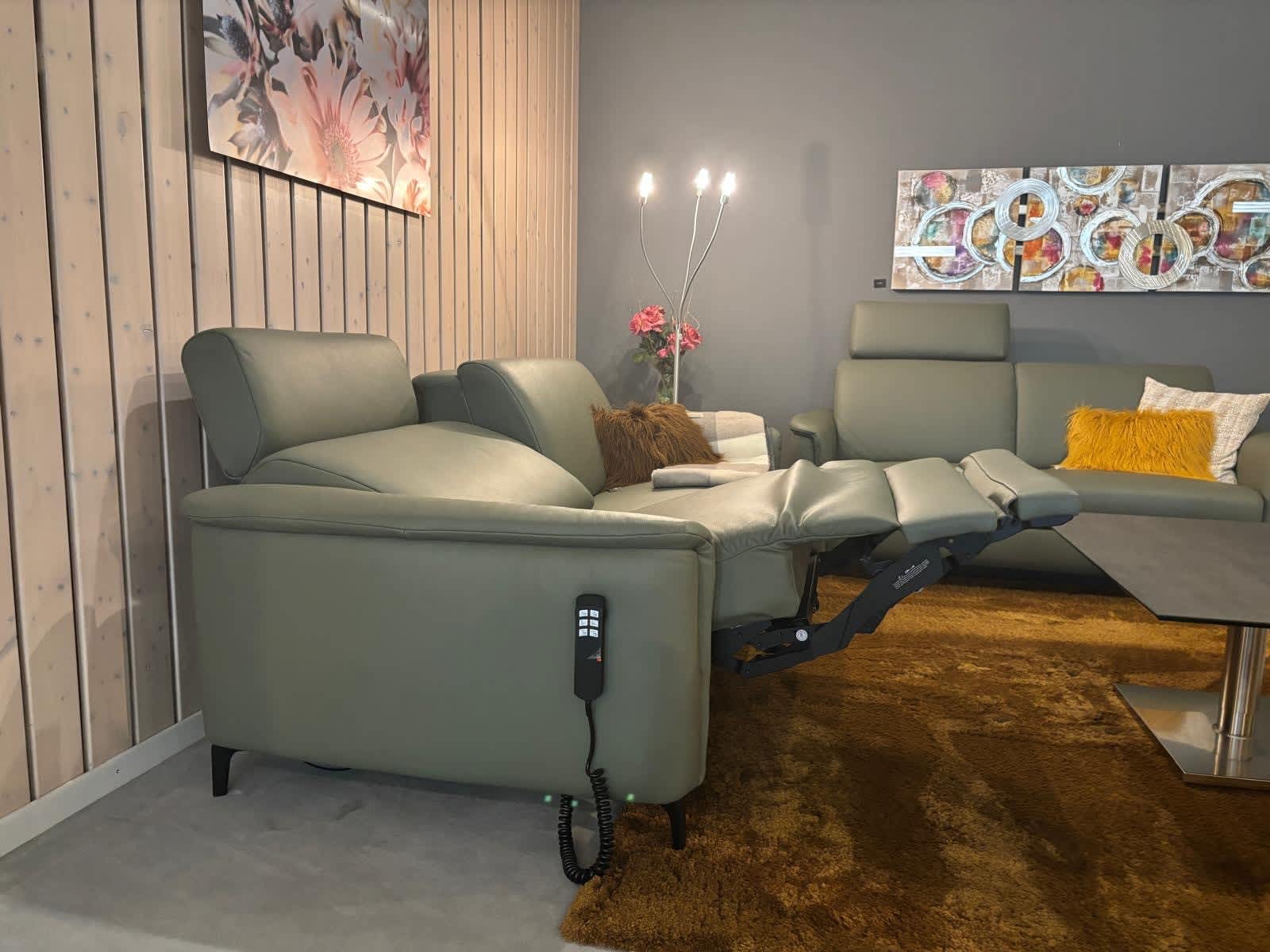 Ein modernes Wohnzimmer mit dem grünen Liegesofa „Ravenna“ aus der PM Oelsa Polstergruppe, einem braunen Teppich und dekorativen Wandbildern. Ein modernes Wohnzimmer mit dem grünen Liegesofa „Ravenna“ aus der PM Oelsa Polstergruppe, einem braunen Teppich und dekorativen Wandbildern.
