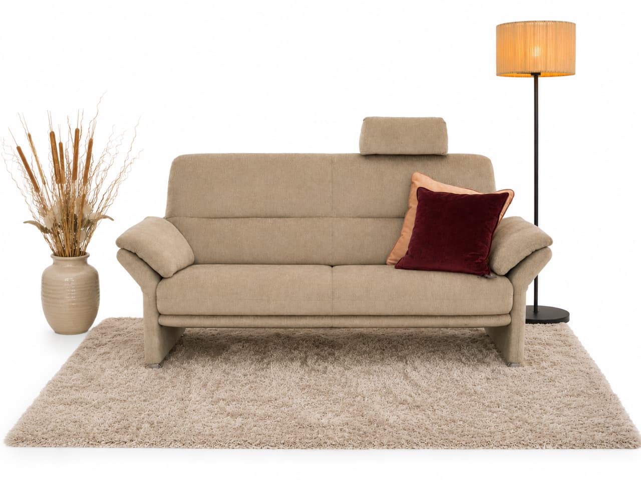 Horst-Sofa „Grimsel“ (2,5-Sitzer) mit einem roten Kissen, einer Lampe und einer Vase mit getrocknetem Gras auf einem beigen Teppich vor weißem Hintergrund. Horst-Sofa „Grimsel“ (2,5-Sitzer) mit einem roten Kissen, einer Lampe und einer Vase mit getrocknetem Gras auf einem beigen Teppich vor weißem Hintergrund.