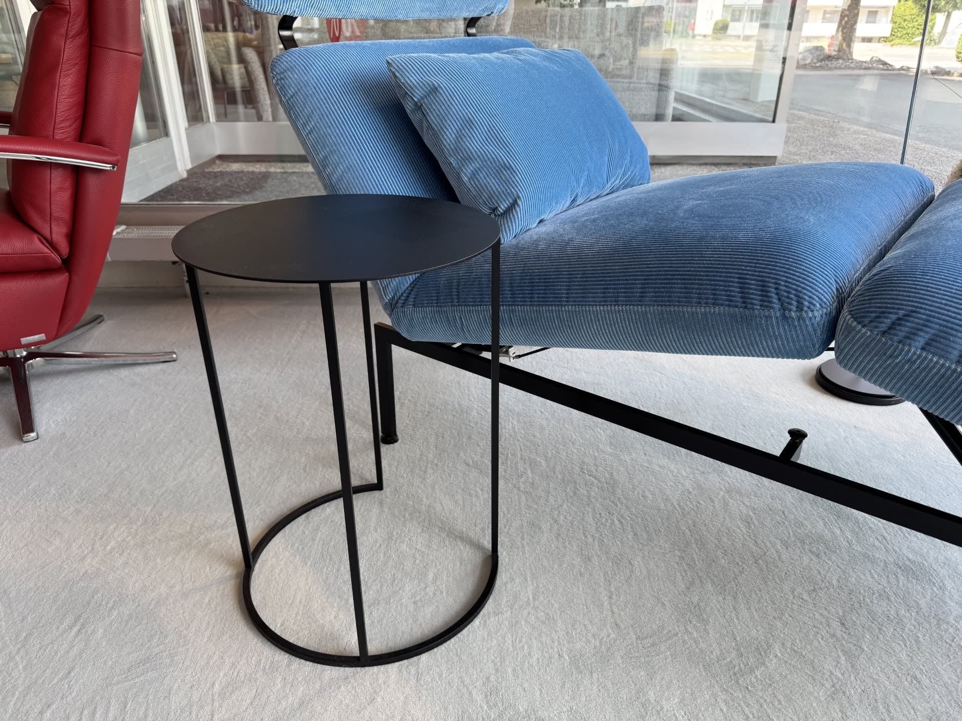 Une table d'appoint ronde Jori „Ascot“ en noir se trouve à côté d'un fauteuil lounge bleu avec coussins, posé sur un sol en tapis clair. Une table d'appoint ronde Jori „Ascot“ en noir se trouve à côté d'un fauteuil lounge bleu avec coussins, posé sur un sol en tapis clair.
