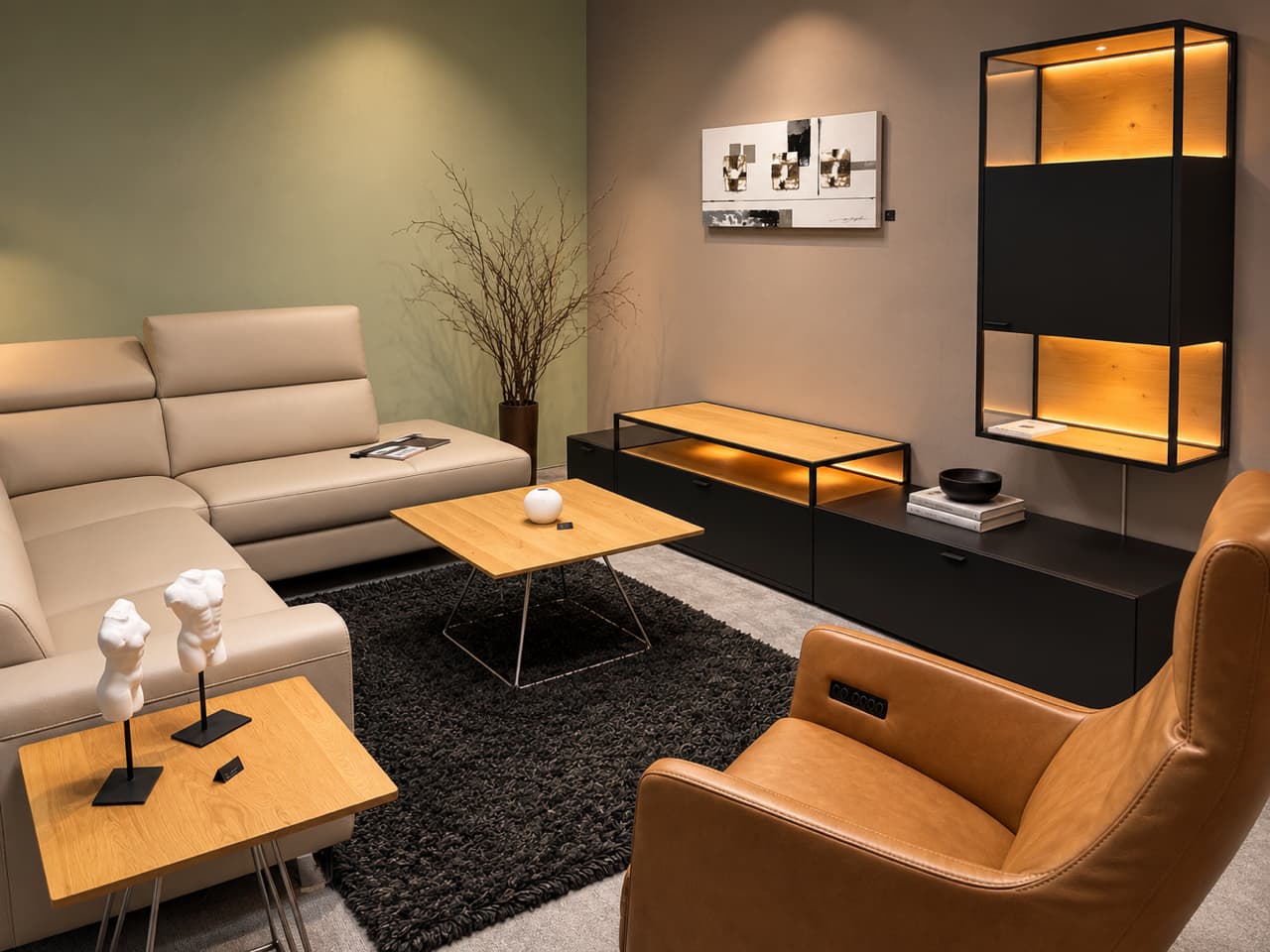 Modernes Wohnzimmer mit der Venjakob-Wohnwand „Plan X6“, ergänzt durch ein beiges Sofa, einen hellbraunen Sessel, Holztische, schwarze Akzente und eine warme Beleuchtung. Modernes Wohnzimmer mit der Venjakob-Wohnwand „Plan X6“, ergänzt durch ein beiges Sofa, einen hellbraunen Sessel, Holztische, schwarze Akzente und eine warme Beleuchtung.