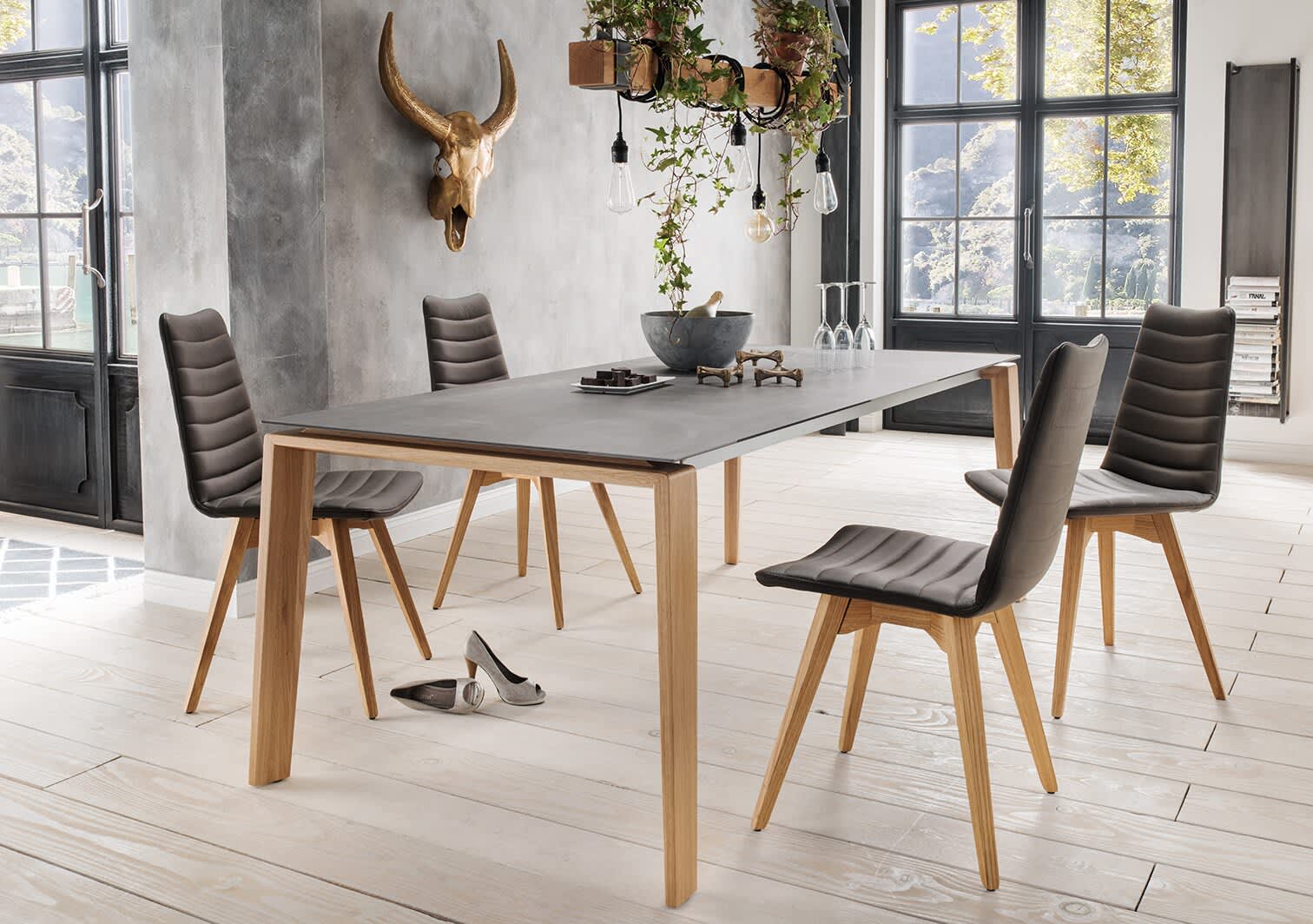 Modernes Esszimmer mit dem grauen Sit Mobilia Tisch Olympia Turin, vier Stühlen, Hängepflanzen und Schuhen auf einem hellen Holzboden. Modernes Esszimmer mit dem grauen Sit Mobilia Tisch Olympia Turin, vier Stühlen, Hängepflanzen und Schuhen auf einem hellen Holzboden.