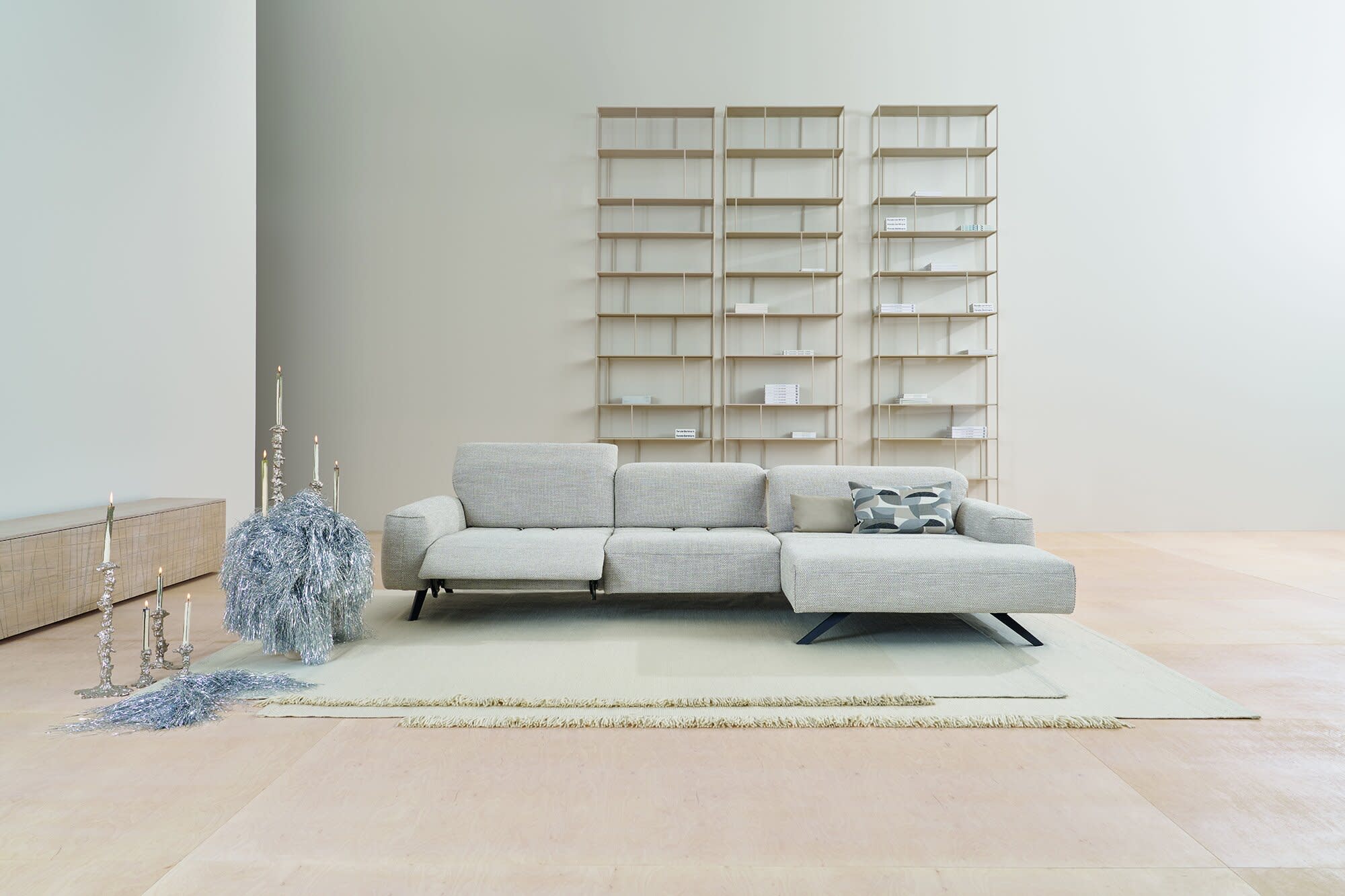 Modernes minimalistisches Wohnzimmer mit dem Himolla Sofa Signa 1552 in Hellgrau, ergänzt durch Regale und minimale dekorative Akzente. Modernes minimalistisches Wohnzimmer mit dem Himolla Sofa Signa 1552 in Hellgrau, ergänzt durch Regale und minimale dekorative Akzente.