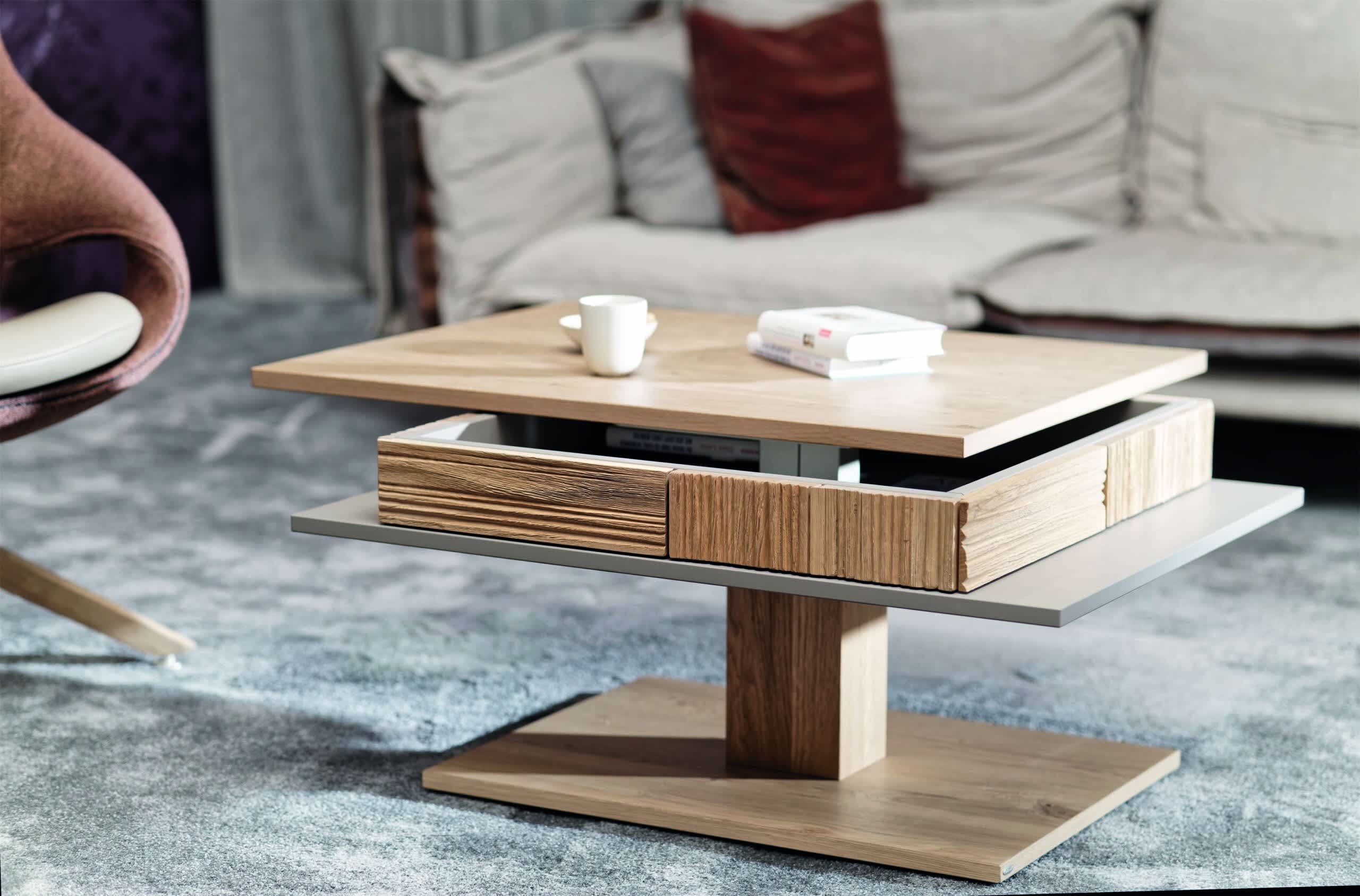 Der Voglauer Salontisch LAC77 ist ein moderner Couchtisch aus Holz mit drehbaren Etagen, auf dem Bücher und eine Tasse in einem gemütlichen Wohnzimmer stehen. Der Voglauer Salontisch LAC77 ist ein moderner Couchtisch aus Holz mit drehbaren Etagen, auf dem Bücher und eine Tasse in einem gemütlichen Wohnzimmer stehen.