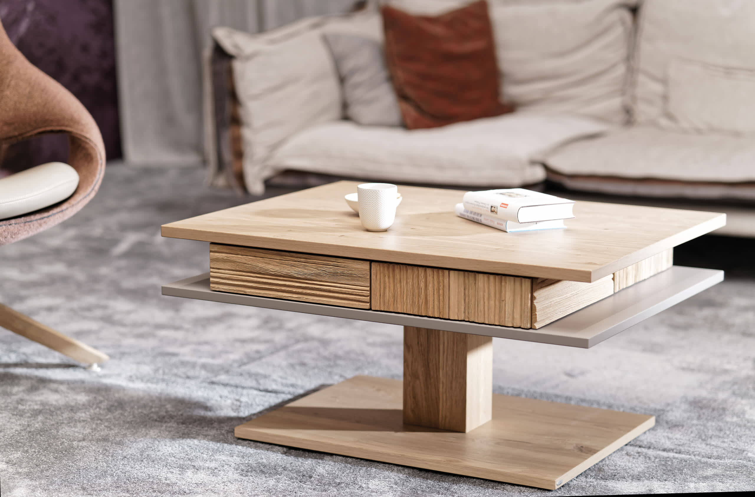Der Voglauer Salontisch LAC77, ein moderner Couchtisch aus Holz mit Büchern und einer Tasse, steht in einer gemütlichen Wohnlandschaft mit einem Sofa im Hintergrund. Der Voglauer Salontisch LAC77, ein moderner Couchtisch aus Holz mit Büchern und einer Tasse, steht in einer gemütlichen Wohnlandschaft mit einem Sofa im Hintergrund.