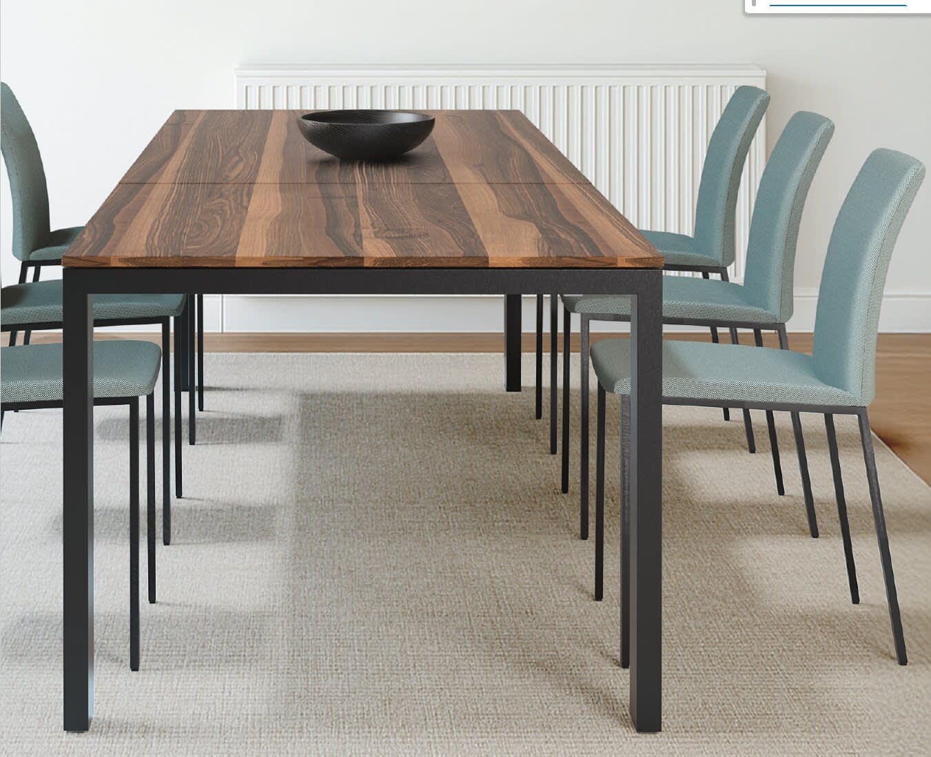 Une table à manger moderne avec un plateau en bois, entourée de six fauteuils Sit Mobilia Pavia bleu clair et d'un bol noir posé sur la table. Une table à manger moderne avec un plateau en bois, entourée de six fauteuils Sit Mobilia Pavia bleu clair et d'un bol noir posé sur la table.