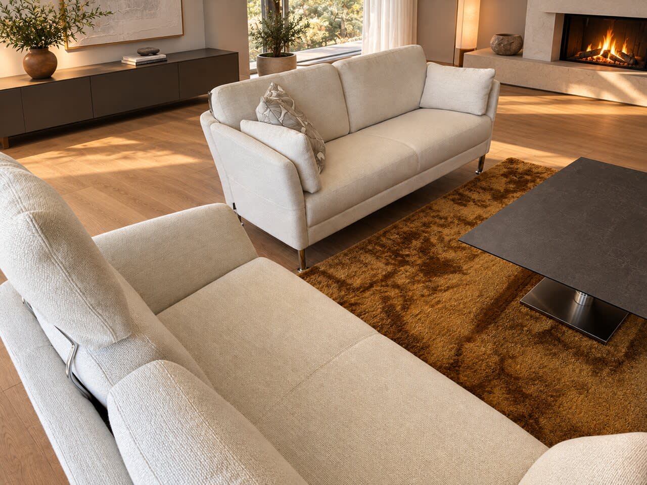 Zwei cremefarbene Sofas der Intertime-Polstergruppe „Nimbus“ stehen um einen dunklen Couchtisch auf einem braunen Teppich. Zwei cremefarbene Sofas der Intertime-Polstergruppe „Nimbus“ stehen um einen dunklen Couchtisch auf einem braunen Teppich.