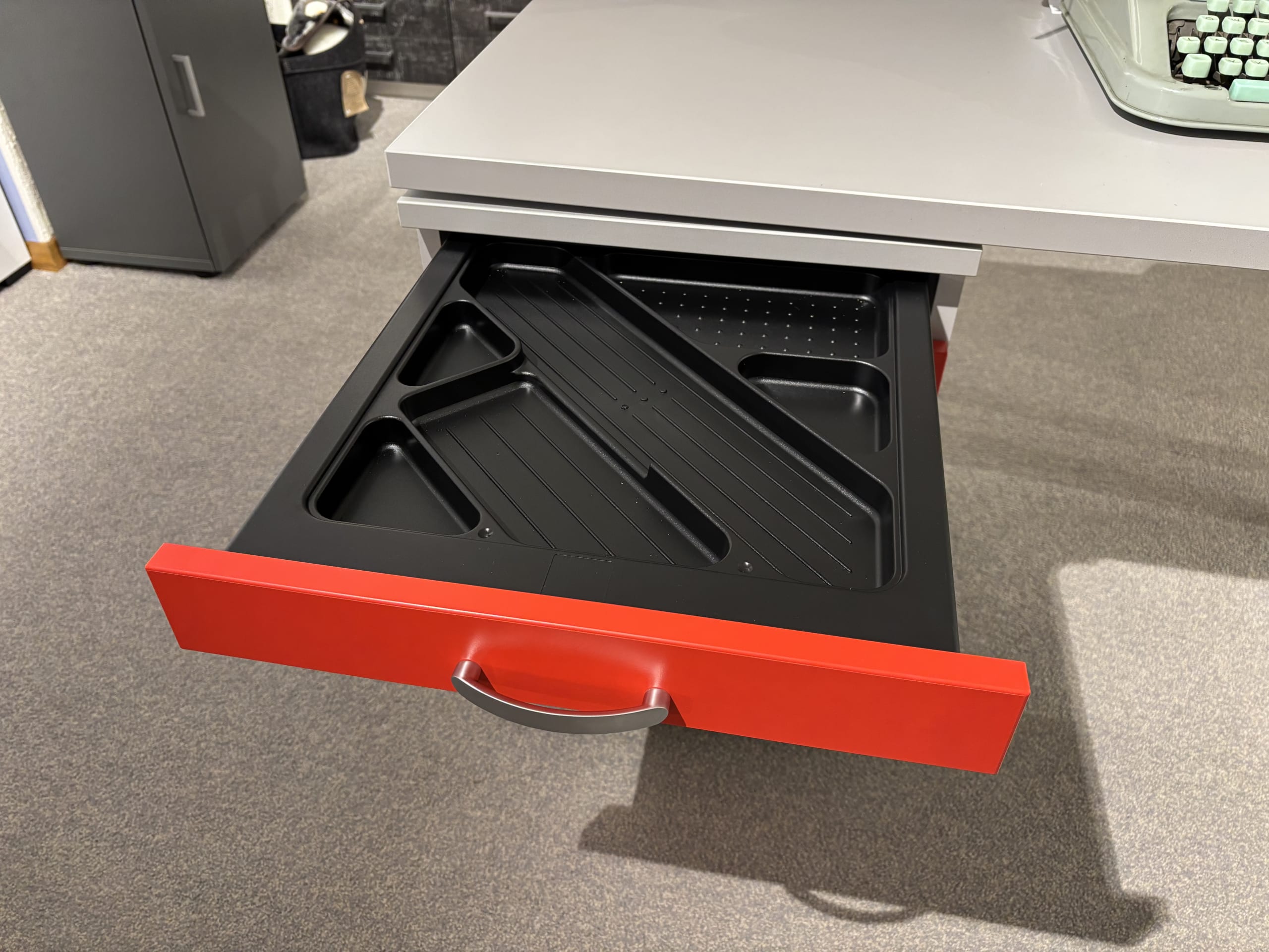 Ouvrez le tiroir rouge du bureau, qui contient un plateau de rangement noir provenant de l'ensemble de mobilier de bureau avec 3 boîtes à fenêtres.