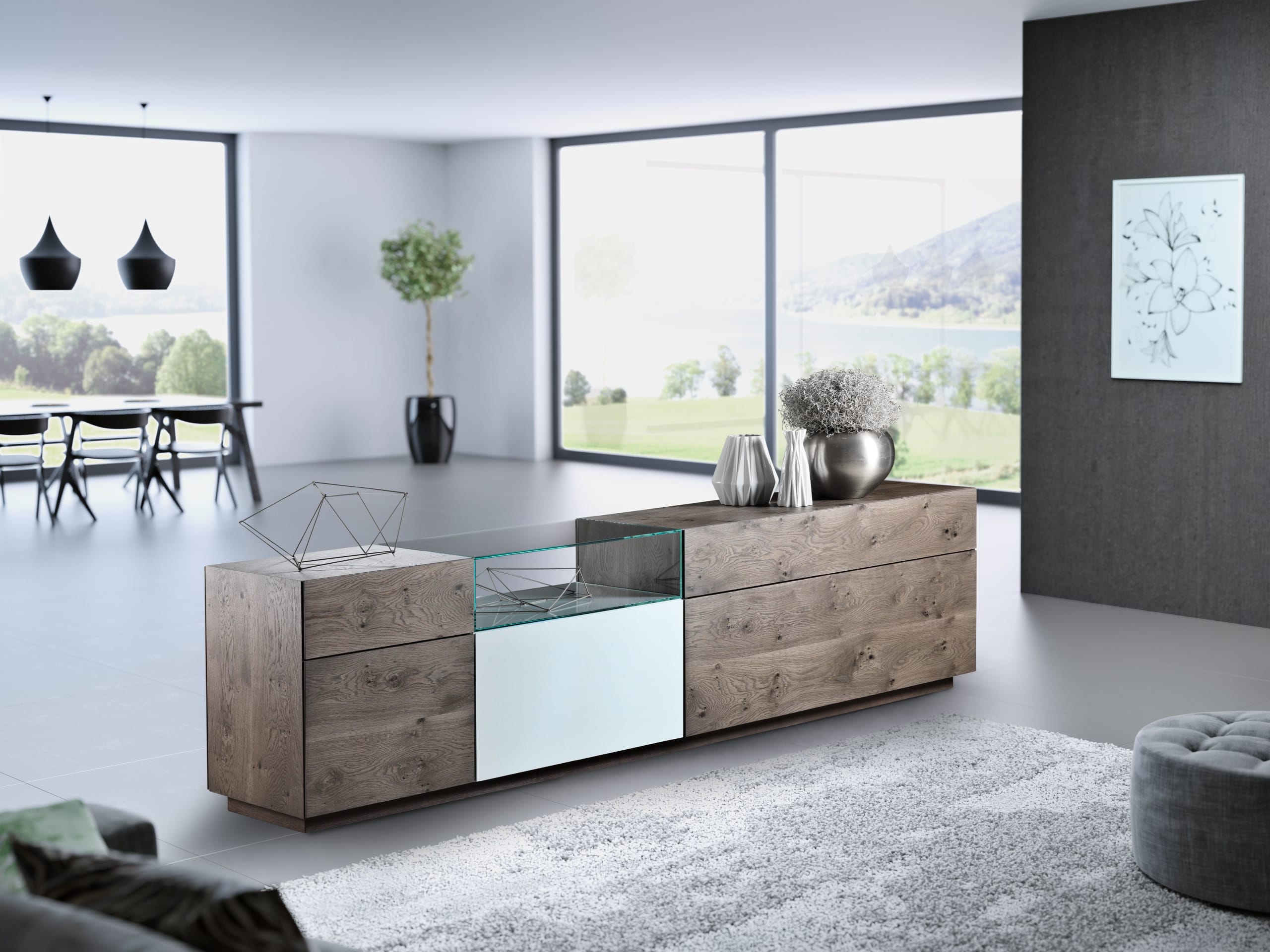 Un salon moderne avec le buffet combiné Sona Living, décoré d'objets décoratifs, de grandes fenêtres et une vue pittoresque sur les montagnes et un lac. Un salon moderne avec le buffet combiné Sona Living, décoré d'objets décoratifs, de grandes fenêtres et une vue pittoresque sur les montagnes et un lac.