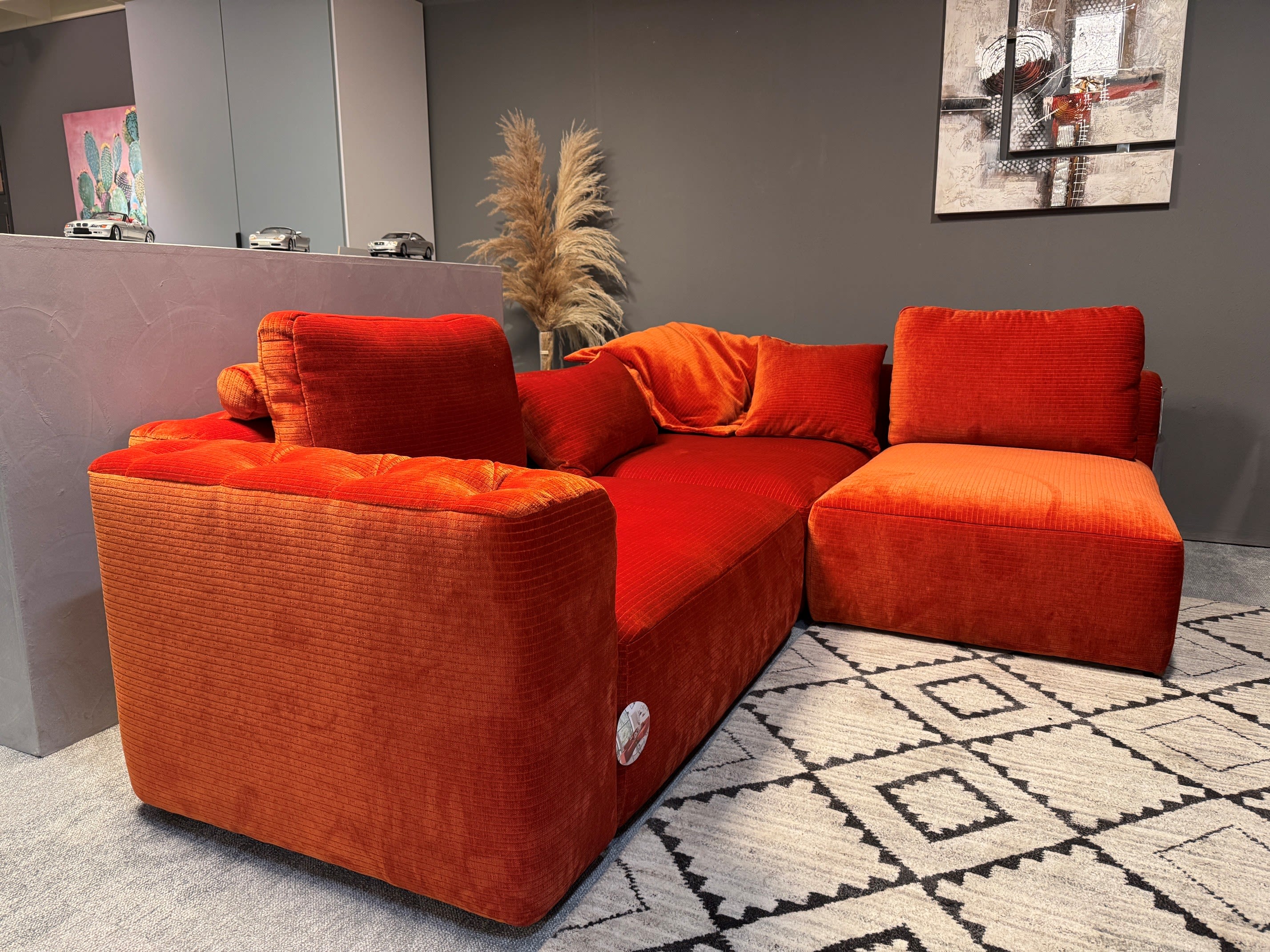 Das Candy Sofa Club House, ein kühnes rotes Sektionssofa aus Samt, steht auf einem gemusterten Teppich in einem modernen Wohnzimmer mit dunklen Wänden. Das Candy Sofa Club House, ein kühnes rotes Sektionssofa aus Samt, steht auf einem gemusterten Teppich in einem modernen Wohnzimmer mit dunklen Wänden.