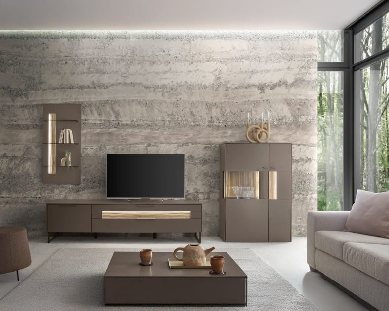 Ein modernes Wohnzimmer mit der SALE 25 Wohnkombination Linee, mit dunklen Möbeln, einem TV-Gerät und großen Fenstern mit Waldblick.