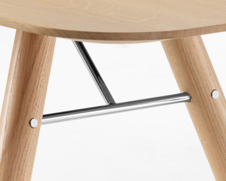 Nahaufnahme des Holzbeins des Esstischs Akio mit einer Metallstütze und einer Sitzfläche aus hellem Holz.