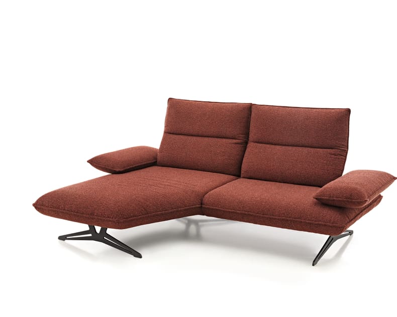 Die Koinor Polstergruppe Caio ist ein modernes rotes Sektionssofa mit schwarzen Metallfüßen und einer verlängerten Chaiselongue auf der linken Seite.
