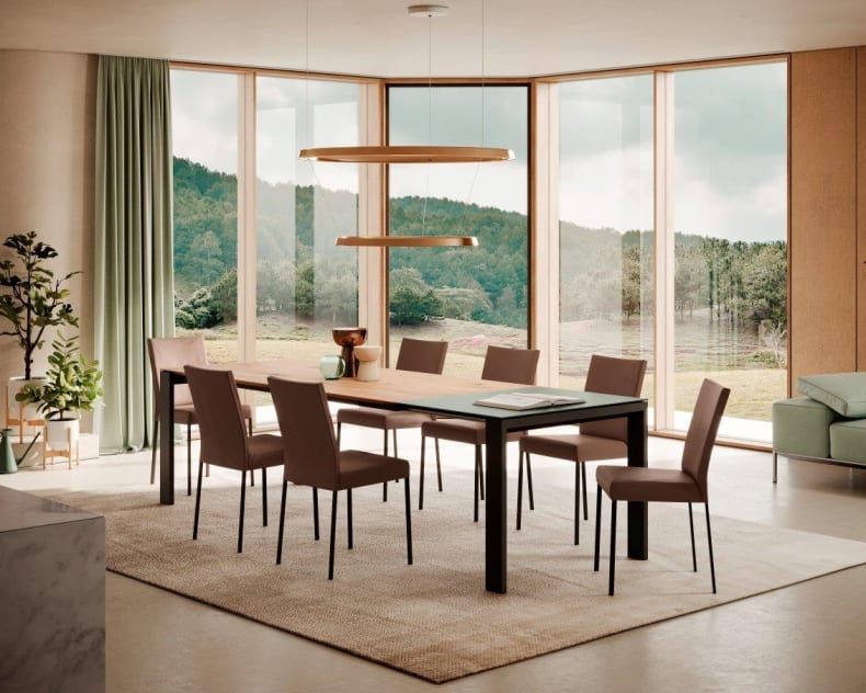 Salle à manger moderne avec de grandes fenêtres, la table à manger rectangulaire Maleo de Willisau, six chaises et une vue sur les collines verdoyantes à l'extérieur.