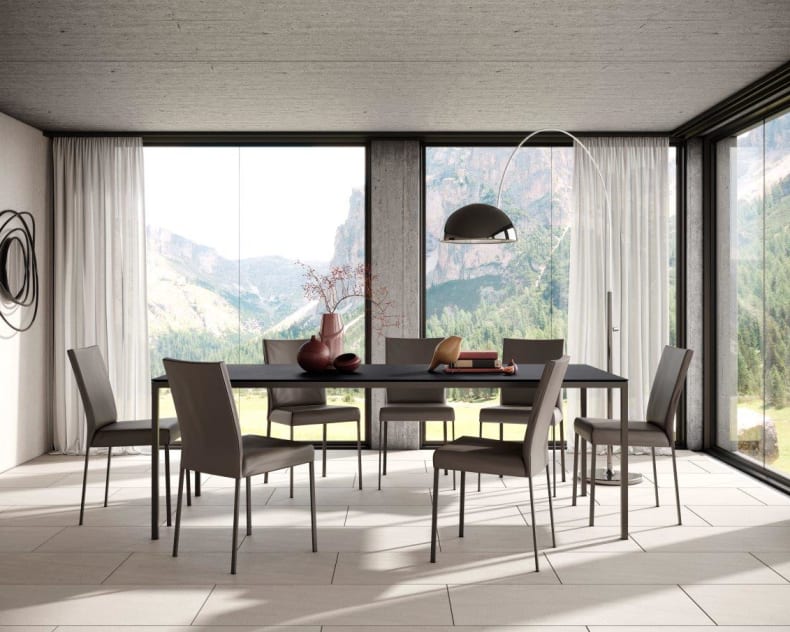 Salle à manger moderne avec de grandes fenêtres, vue sur la montagne, table à manger minimaliste Willisau Dino, six chaises et décor contemporain.