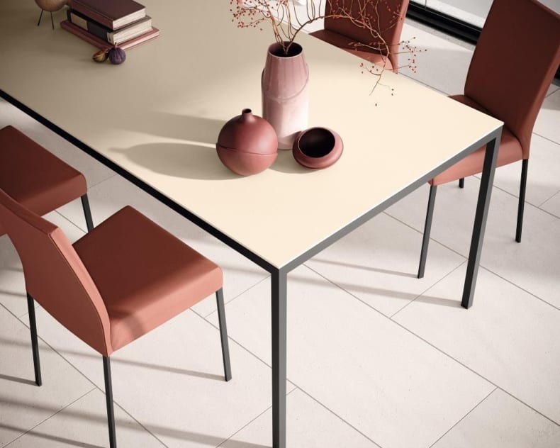 Table à manger minimaliste avec chaises Willisau Ambient couleur rouille, plateau beige et vases en céramique disposés dessus.