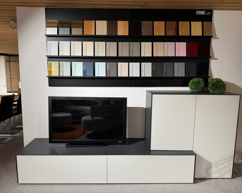 Die MAB TV-Möbel Nara-Konsole besteht aus einem Schrank, zwei grünen Dekokugeln und einem Wanddisplay mit verschiedenen Farbmustern darüber.