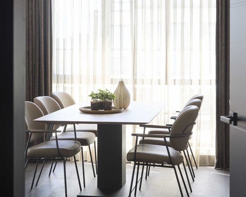 Minimalistisches Esszimmer mit einem rechteckigen Tisch, sechs Stühlen von bert plantagie Stuhl Blake Schlitten und transparenten Vorhängen, die den Raum mit natürlichem Licht erfüllen.