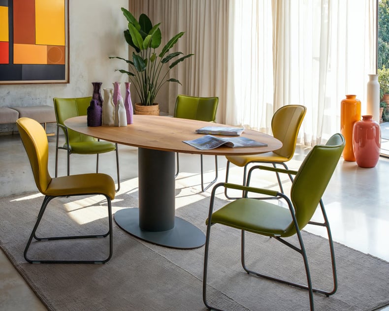 Modernes Esszimmer mit Holztisch, bert plantagie Stuhl Blake Schlitten grüne Stühle, Pflanzen, große Fenster und abstrakte Kunst an der Wand.