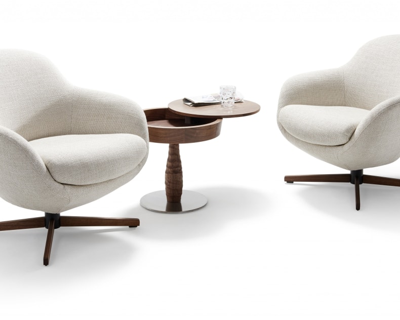 Zwei cremefarbene Sessel von Signet Sessel Messina Jester klein stehen einander gegenüber, getrennt durch einen kleinen runden Holztisch mit Tassen.