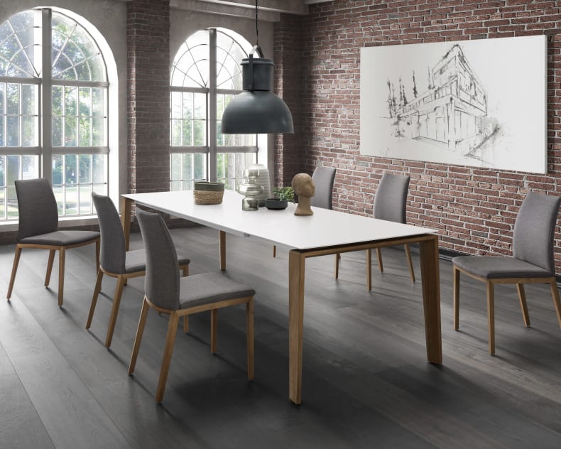 Modernes Esszimmer mit dem Sit Mobilia Tisch Olympia Turin, sechs Stühlen, Backsteinwänden, großen Fenstern und einem skizzenhaften Kunstwerk.