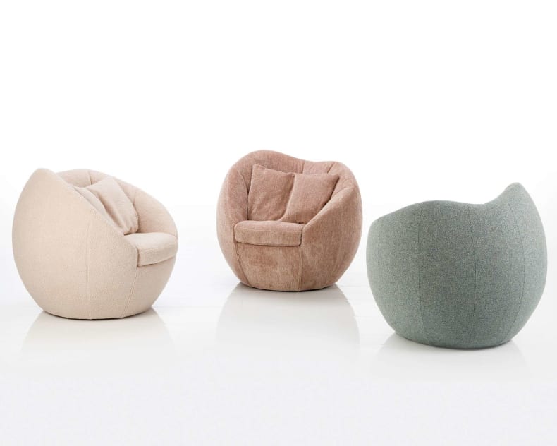 Drei runde, gepolsterte Brühl Sessel Azur Lounge Chairs in Beige, Rosa und Grün stehen auf weißem Grund.