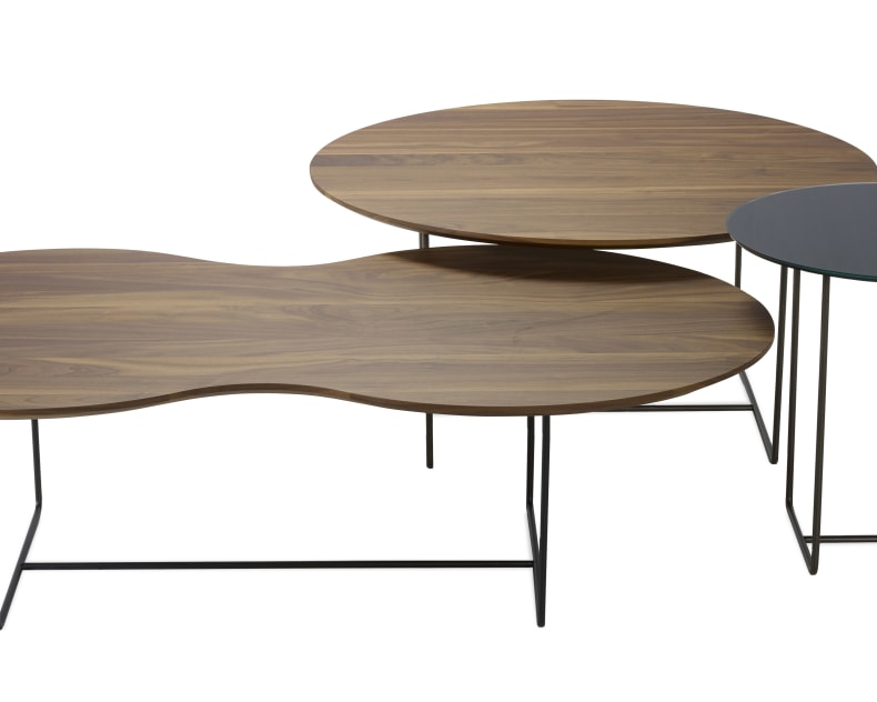 Drei moderne Schachteltische mit dünnen Metallbeinen und Holzplatten, einer davon mit einer runden Glasplatte.