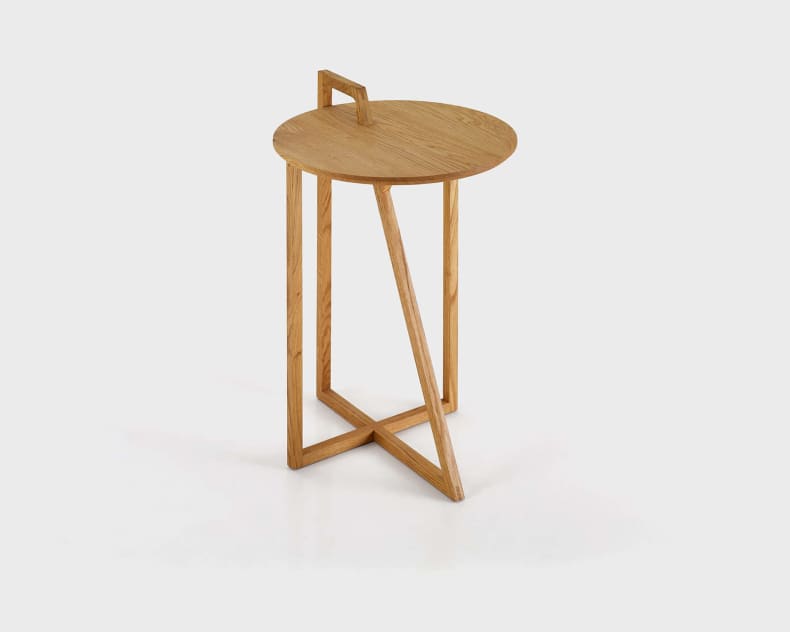 Der Salontisch Tabletime Corner 40 ist ein moderner runder Beistelltisch aus Holz mit einem Griff und einem geometrischen Fuß mit gekreuzten Beinen.