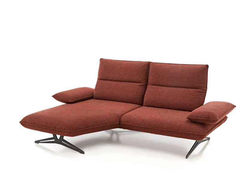 Die Koinor Polstergruppe Caio ist ein modernes rotes Sektionssofa mit schwarzen Metallfüßen und einer verlängerten Chaiselongue auf der linken Seite.