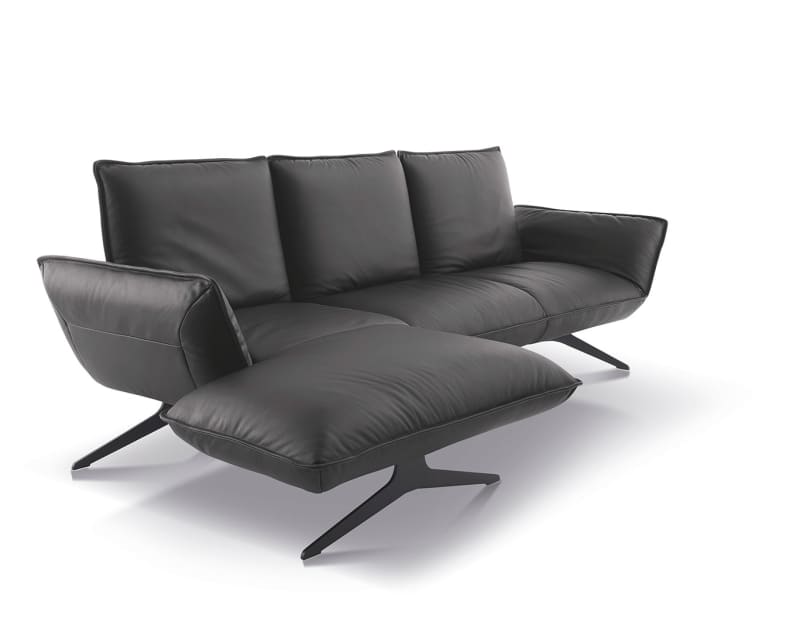 Das Koinor Sofa Buddy ist ein modernes schwarzes Ledersofa mit passender Ottomane und schlanken Metallbeinen, die vor einem weißen Hintergrund präsentiert werden.
