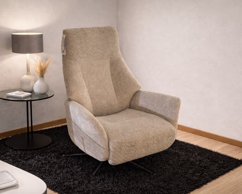 Der beigefarbene Sessel Stylux 8115 von Hjort Knudsen steht auf einem schwarzen Teppich neben einem runden Glastisch mit einer Lampe, einer Vase und einem Buch in einem modernen Raum.