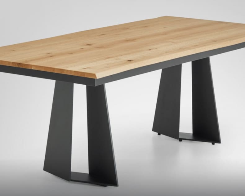 Der Venjakob Tisch Chic ist ein moderner rechteckiger Holztisch mit abgewinkelten schwarzen Metallbeinen auf hellgrauem Hintergrund.