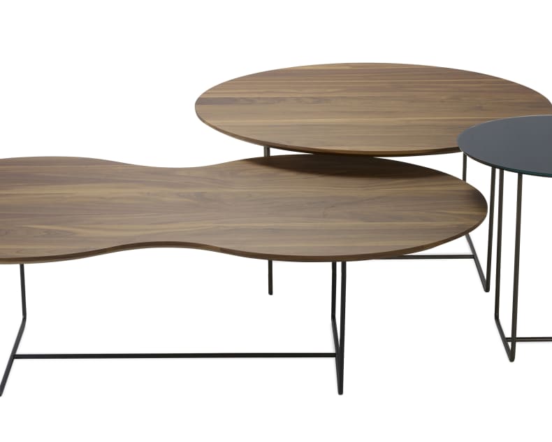 Drei moderne Schachteltische mit dünnen Metallbeinen und Holzplatten, einer davon mit einer runden Glasplatte.