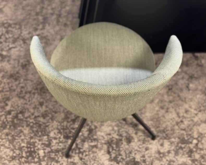 Vue de dessus de la chaise Willisau Loreo (copie), une chaise moderne en tissu vert clair avec des pieds en métal noir, posée sur un sol moucheté.