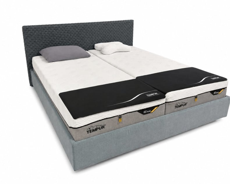 Das Röwa Bett Someo ist ein modernes, graues Polsterbett mit zwei Matratzen mit schwarzen TEMPUR-Bezügen und weißen Kissen.