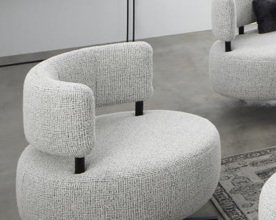 Der Ponsel Recamiere Organic (Kopie) Sessel mit seinen eleganten grauen Rundungen und dem Drehfuß steht auf einem Betonboden. Im Hintergrund stehen ein Konsolentisch und ein Kunstwerk.