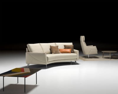 Modernes Wohnzimmer mit dem Sofa Thalia 9182 in Creme, ergänzt durch einen Sessel, einen Couchtisch und Akzentkissen auf einem weißen Boden.