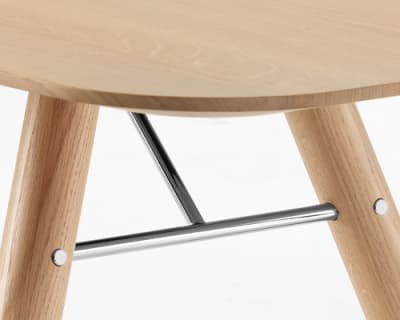 Gros plan de l&#39;os en bois de la table à manger Akio avec un support en métal et un siège en bois clair.